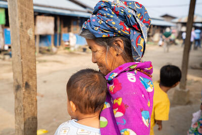 A woman in a camp for displaced people in Kachin State, Myanmar, holds a young child. It is estimated that more than 3 million people across the country have been forced to flee their homes as conflict surges between the Myanmar Armed Forces and various armed groups. March 2024. Photo: UNA-UK/Christina Powell.