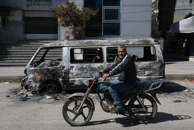 A man rides past a burned-out vehicle in Jablah town, Lattakia Governorate, following the recent escalation in violence across Syria's coastal areas. 